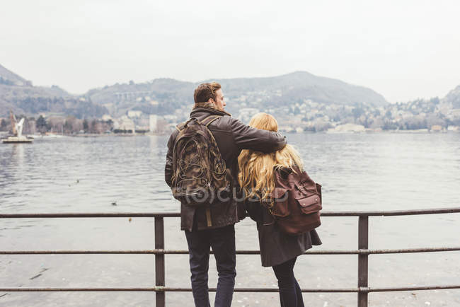 Rear view of young couple looking out on lakeside, Lake Como, Italy — Stock Photo