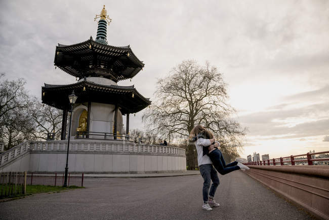 Romantic young man lifting girlfriend in Battersea Park, London, UK — Stock Photo