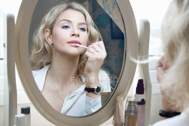 Ragazza adolescente guardando allo specchio, applicando il make-up — Foto stock