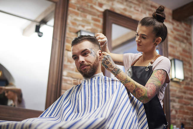 Hairdresser cutting customer's hair — Stock Photo