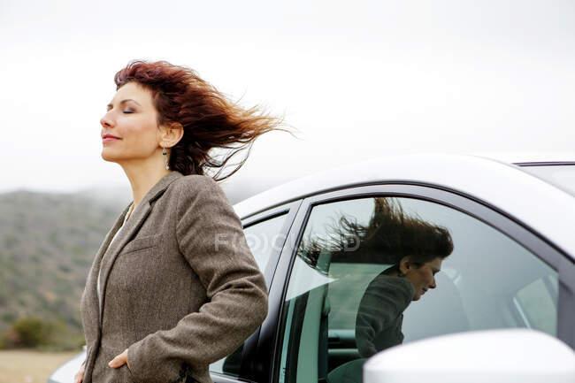 Businesswoman by car in fresh air with eyes closed — Stock Photo
