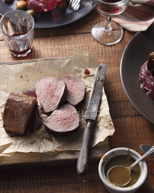 Steak de châteaubriand tranché avec vinaigrette et couteau — Photo de stock