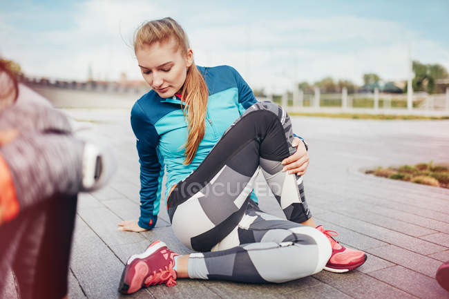 Female runners doing warm up stretches on pier — Stock Photo