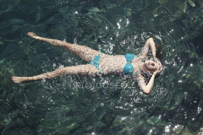 Дівчина-підліток плаває з закритими очима в морі — стокове фото