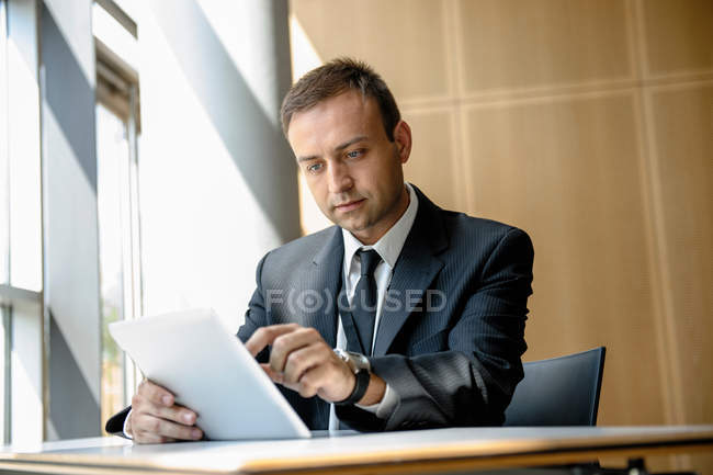 Empresario que usa tableta en el escritorio - foto de stock