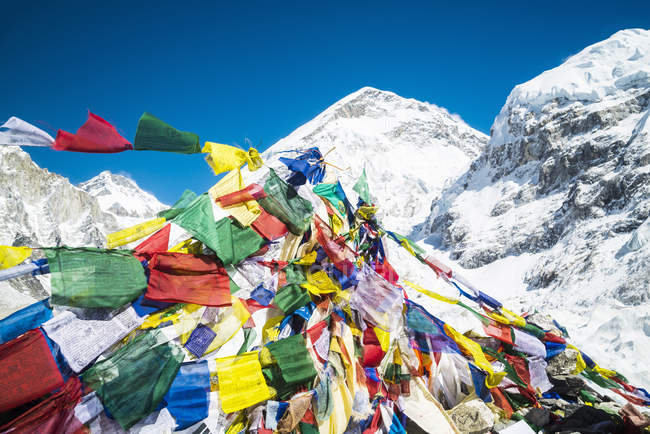 Drapeau de prière multicolore avec des montagnes enneigées sur fond — Photo de stock