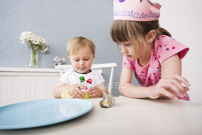 Baby boy and pre-adolescent girl playing with birthday cupcake — Stock Photo