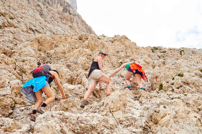 Vista de bajo ángulo de las mujeres que suben a la montaña rocosa, Austria - foto de stock
