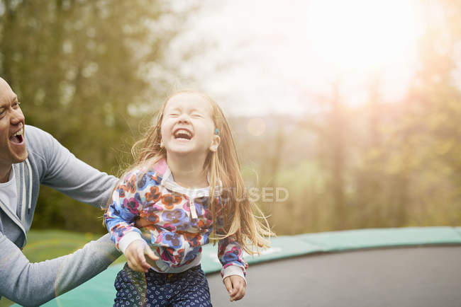 Padre e hija jugando juntos en el trampolín - foto de stock