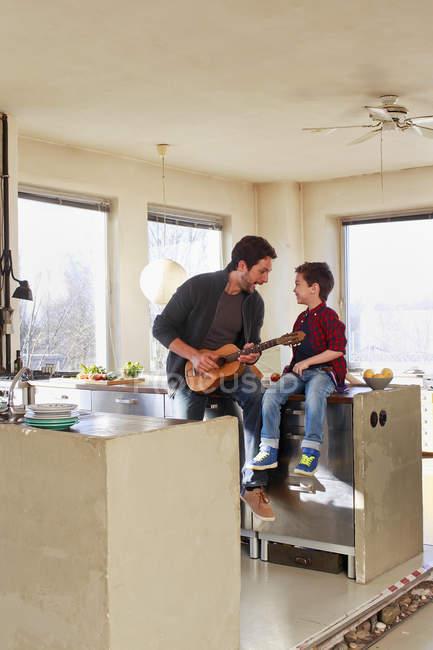 Pai e filho tocando guitarra na cozinha — Fotografia de Stock