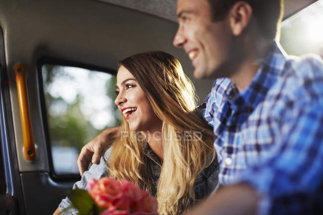 Mujer joven con novio y ramo de rosas en taxi de la ciudad - foto de stock