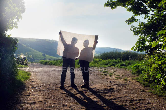 Couple randonnée sur terre piste lecture carte — Photo de stock