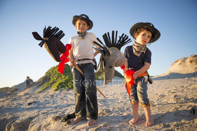 Dois irmãos vestidos de cowboys com cavalos de passatempo — Fotografia de Stock