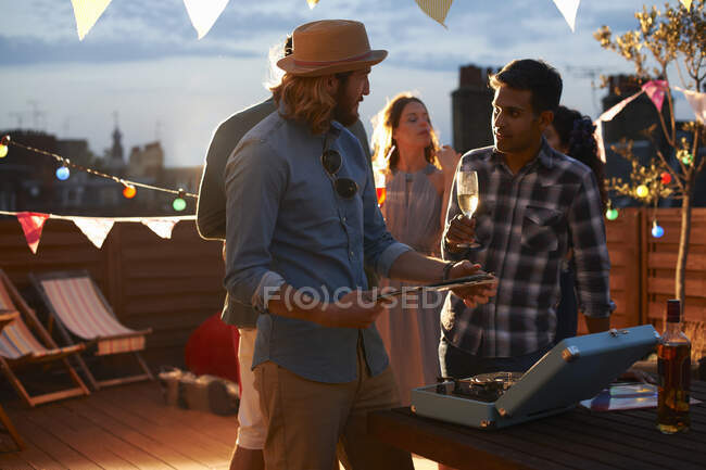 Man putting on music at early evening party — Stock Photo