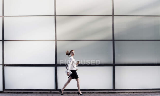 Businesswoman walking holding hot drink — Stock Photo