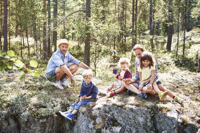Family sitting on rocks in forest — Stock Photo