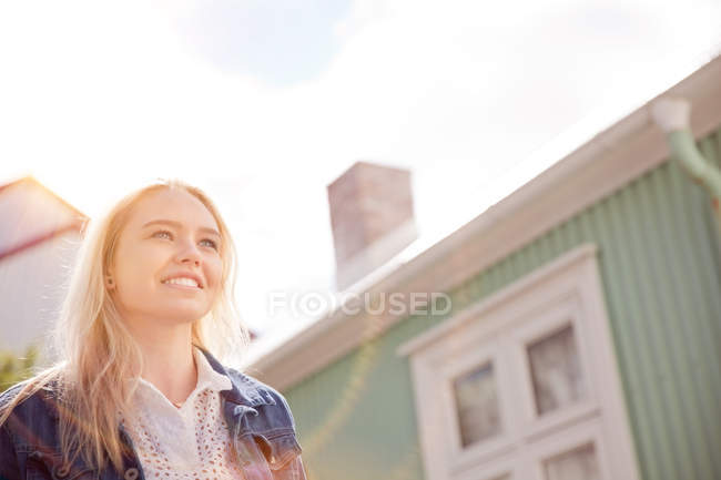 Vue en angle bas de la maison extérieure et blonde adolescente aux cheveux regardant ailleurs souriant, Reykjavik, Islande — Photo de stock