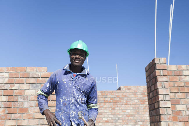 Retrato del constructor con sombrero duro mirando a la cámara sonriendo - foto de stock