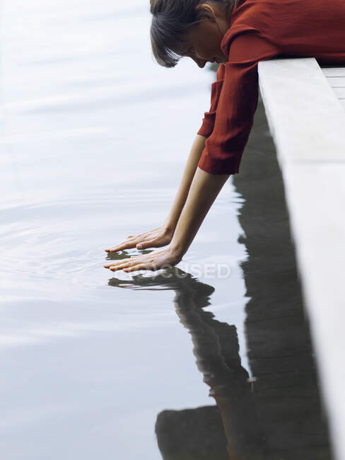 Donna sdraiata davanti al molo che tocca la superficie dell'acqua, Copenaghen, Danimarca — Foto stock