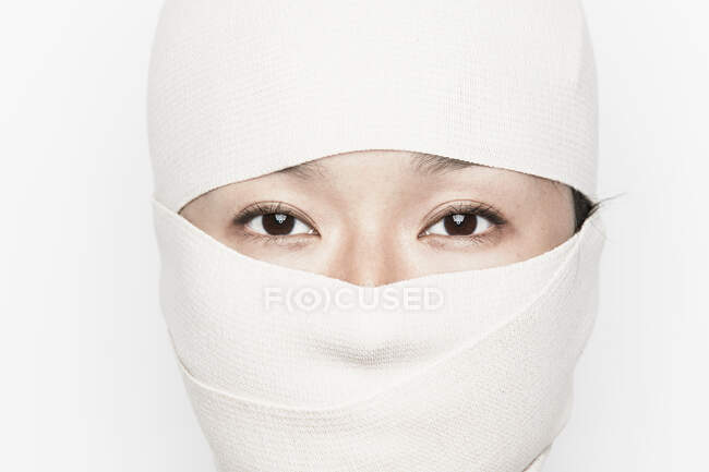 Mujer con la cara vendada, solo ojos visibles - foto de stock