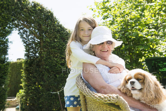 Retrato de abuela y nieta con perro - foto de stock
