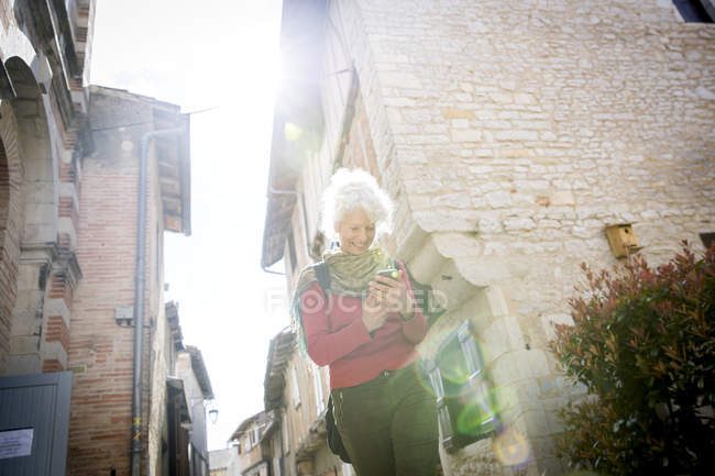 Donna in strada a guardare smartphone sorridente. Bruniquel, Francia — Foto stock