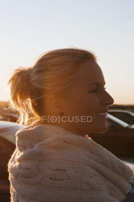 Усміхнена жінка середнього віку на парковці на заході сонця — стокове фото