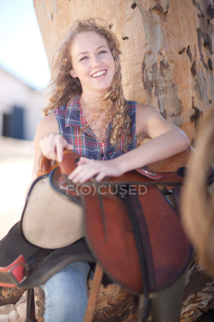 Young woman holding saddle — Stock Photo