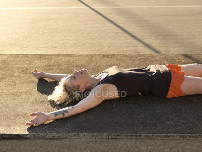 Exhausted young woman taking a training break in parking lot — Stock Photo