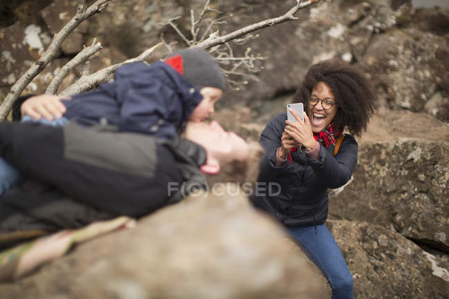 Woman taking photo of man holding son, laughing — Stock Photo