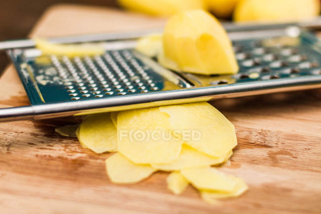Kartoffel mit Reibe auf Holzbrett — Stockfoto