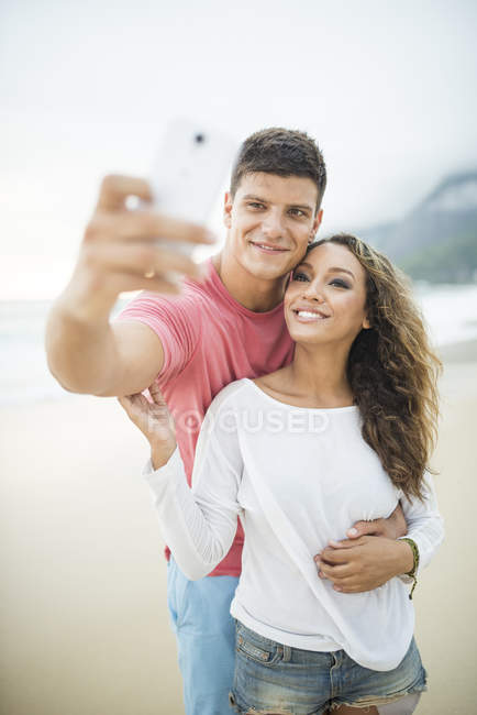 Young couple taking self portrait on Ipanema Beach, Rio de Janeiro, Brazil — Stock Photo