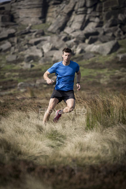 Чоловічий бігун працює вниз від Stanage краю, Peak District, Дербішир, Велика Британія — стокове фото