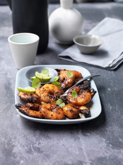 Chargrilled prawns with slices of lime on plate — Stock Photo