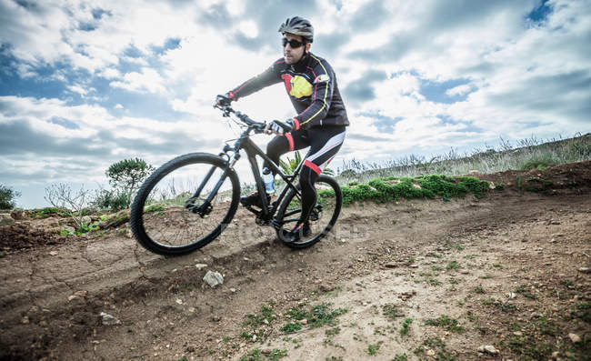 Mittlerer erwachsener männlicher Mountainbiker rast auf Track Corner, cagliari, sardinien, italien — Stockfoto