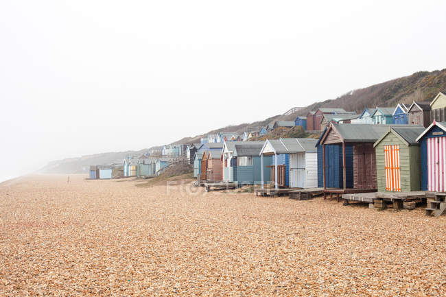 Cabanes de plage en rangée sur la plage de galets — Photo de stock
