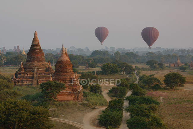 Balões de ar quente e templos antigos ao pôr do sol, Bagan, Birmânia — Fotografia de Stock