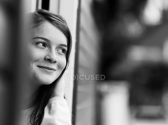 Sonriente chica de pie en la puerta, en blanco y negro - foto de stock