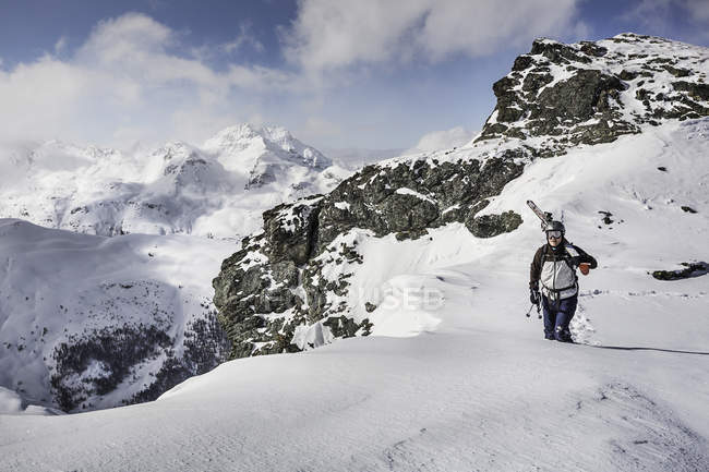 Mid adult male skier walking along top of mountain with skis, Corvatsch, Suisse — Photo de stock