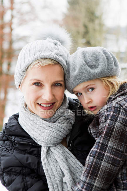 Madre llevando hija en la nieve - foto de stock