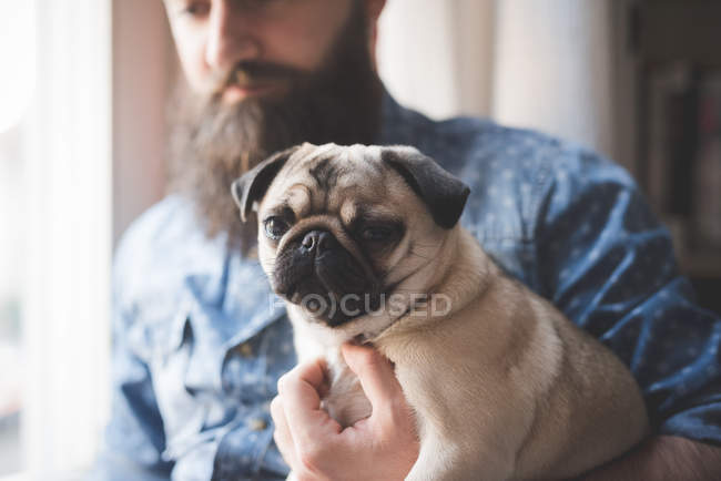 Jovem barbudo carregando cão em braços — Fotografia de Stock
