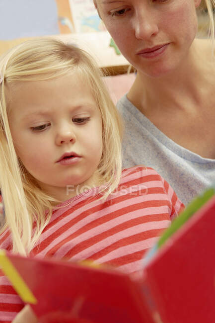Madre che legge libro di foto con figlia — Foto stock