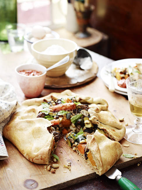 Vegetable freeform pie on messy table — Stock Photo