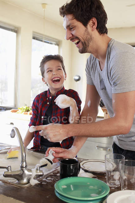 Pai e filho com sabão suds em mãos — Fotografia de Stock
