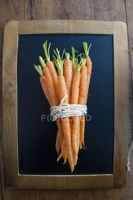 Montón de zanahorias en la pizarra negra, bodegón - foto de stock