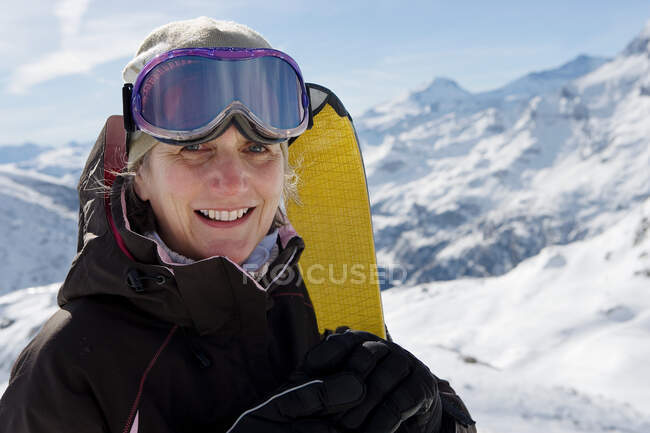 Mature female skier holding Skis — Stock Photo