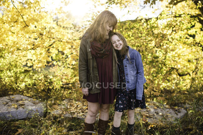 Madre e hija sonriendo en la zona boscosa - foto de stock