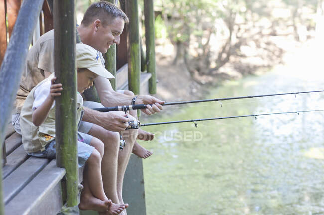 Отец и сыновья рыбачат у реки — стоковое фото