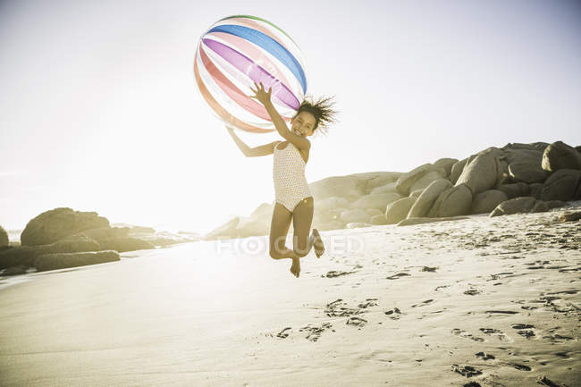 Mädchen mit Ball springt am Strand — Stockfoto