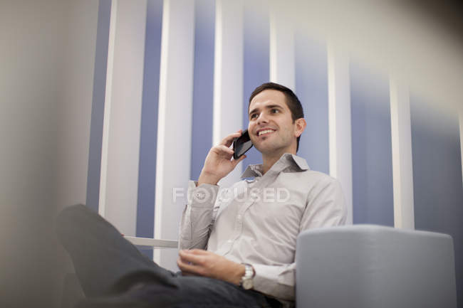 Взрослый мужчина на смартфоне в офисе, вид с низкого угла — стоковое фото